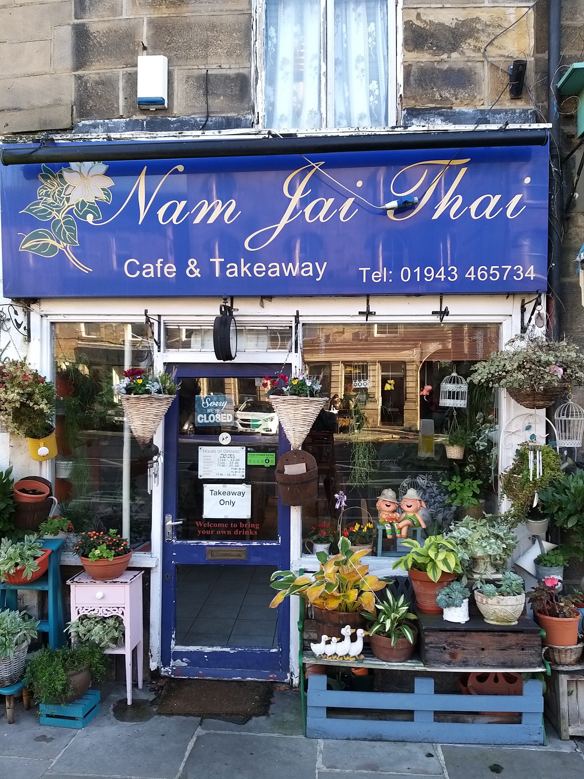Nam Jai Thai's blue and gold shopfront with plants at 13 Manor Square, Otley